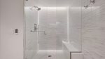 En suite bath featuring quartz vanity, LED mirror, and luxurious shower.