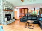 At the heart of Wildhaus: a spacious great room with a river rock decorative fireplace, cozy sectional, and seamless flow into the vibrant, well-stocked kitchen.