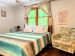 Wake up to wooded views and soft morning light this serene king bedroom blends cheerful touches with natural tranquility.