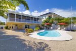 Large private outdoor area with a pool, ample seating, umbrella and dockage