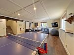 Lower level living space with Smart TV, plenty of seating, and a ping pong table 