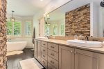 Main level primary bathroom has a large vanity area and separate soaking tub and walk in shower