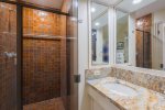 This bathroom features a walk-in shower, granite countertops and a stylish vanity with sink