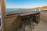 Balcony with bar seating, front row views of the sand, surf, and sunsets