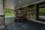 Covered patio on with outdoor dining area, to the right is the main entry door to the house