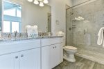 Connected bathroom with double vanity and walk-in glass shower. 