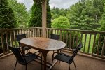 Deck with table overlooking beautifully landscaped lawn
