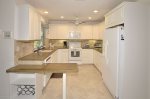 Kitchen with recessed ceiling lighting & white appliances.