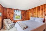 A queen bed and a cozy chair 