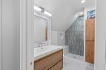 The upstairs full bath offers crisp white finishes and a luxurious glass walk-in shower.