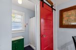 The bathroom features a distinctive red sliding door and a walk-in shower, adding charm and personality to the space.