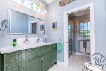 Ensuite bathroom off the king bedroom with double vanity, storage, and coastal finishes for a spa-like feel.