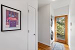 Laundry nook with stacked washer and dryer near exterior door, ideal for towels, swimsuits, and beach days.