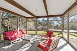 Screened porch lounge with cushioned seating and backyard views, breezy Cape Cod indoor outdoor living in Wellfleet.