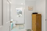 Bathroom hall view with storage, clean finishes, and bright window light, practical Cape Cod vacation convenience.