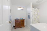 Full bath with tub shower and extra storage, easy for kids, beach towels, and quick cleanups.