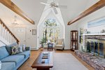 Vaulted living room with exposed beams and brick fireplace, cozy gathering spot after Outer Cape adventures.