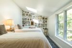 Cheerful twin bedroom with a gallery wall and sunlit window, creating a playful, Cape Cod inspired retreat for little ones.