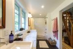 Updated full bath with marble vanity, subway-tiled tub and shower, bright lighting, and plenty of storage for a comfortable stay.