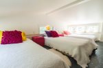 Loft sleeping space with three twin beds, ideal for children, sleepovers, or overflow guests.