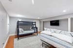 Lower-level bunk room with pyramid bunk, extra bed, and TV, kid-friendly setup for Cape Cod family trips.