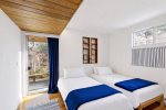 Twin bedroom with two beds and a door to the deck, an easy setup for kids, cousins, or friends.