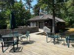 Expansive deck with outdoor dining and umbrella, nestled among trees for a private Cape Cod outdoor living experience.