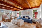 Warm and welcoming living room with dramatic wood beam ceilings, oversized seating, and relaxed coastal style in this Eastham vacation rental.