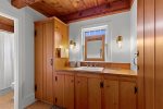 First floor full bathroom offers warm wood cabinetry, generous storage, and a clean, timeless design.