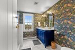 Beautifully finished bathroom features bold designer wallpaper, marble surfaces, and brass accents for a boutique hotel feel.