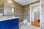 Another view of the upstairs bath showcases the striking wallpaper, marble vanity, and elegant brass details.