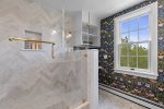 The pristine glass shower with marble tiles elevates this home.