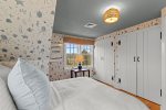 Charming upstairs queen bedroom with playful coastal wallpaper, built in storage, and soft natural light for a calm retreat.
