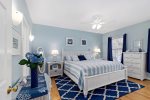Main level king bedroom with soothing coastal palette, ceiling fan, and plenty of space to unpack for your Cape Cod getaway. 