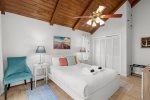 Main level queen bedroom with vaulted wood ceiling, crisp coastal styling, and a calm, private retreat after the beach.