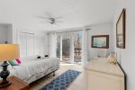 Main level queen bedroom with sliders to the deck, bringing in fresh air and wooded privacy just beyond the glass.
