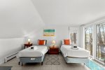 Upper level twin bedroom with two beds and sliding glass doors, great for kids, friends, or flexible group stays.