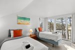 Bright twin bedroom with marsh and treetop views, offering airy upstairs sleeping space in this Wellfleet rental home.