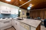 white kitchen cabinets, white appliance package, granite counters, stainless steel sink, blue pendant lights, wood ceiling, dining area, window wall curtains