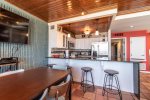breakfast bar, bar stools, dining table, television, stainless steel appliances, saltillo tile, wood ceiling
