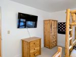 Smart TV, wall mounted connect four game, and dresser space in the Bunk room