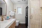 Full bathroom with laundry machines and gorgeous standing tile shower